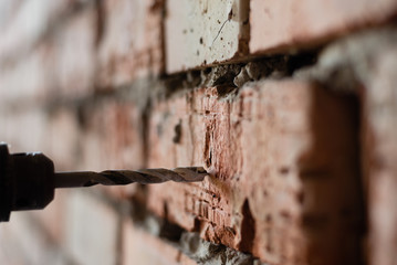 photo close up. drill drills a hole in the brick wall.