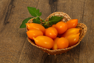 Yellow tomato heap in the wooden bowl