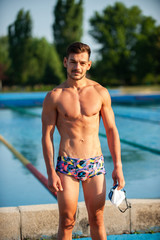 Swimmer standing next to a pool on a sunny morning