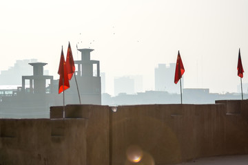 Chinese flags lining Kashgar's renovated Old City wall, with modern buildings in the background.  Kashgar, Xinjiang Uyghur Autonomous Region, China. - obrazy, fototapety, plakaty