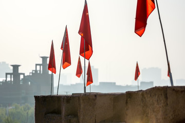 Chinese flags lining Kashgar's renovated Old City wall, with modern buildings in the background.  Kashgar, Xinjiang, China. - obrazy, fototapety, plakaty
