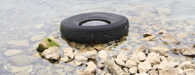 ein alter Reifen liegt am Ufer
