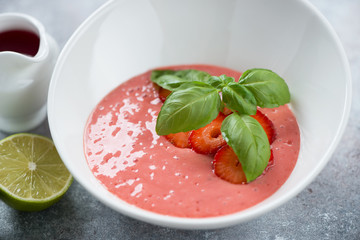 Close-up of soup with fresh strawberries in a white bowl, studio shot