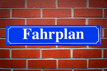 Fahrplan Schild blau an Backsteinwand