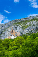 Montenegro, Ancient building of ostrog monastery carved out of rock wall cliff visited by hundreds of thousands pilgrims every year to see miracles on holy ground