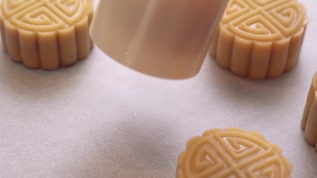 Homemade cantonese moon cake before baking - Woman making festive pastry with shaping mold on baking tray for traditional festival, close up.