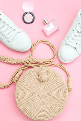 White trendy sneakers  and feminine accessories on pink pastel background. Front view.