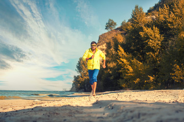 bearded athlete runs along the sandy beach. active lifestyle