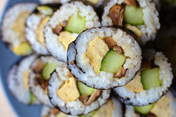Vegetarian rolled Maki sushi filled with egg, cucumber and asian shitake mushrooms stacked on a plate