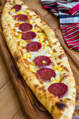 Traditional Turkish Sucuk Pide at Kebab Restaurant on Wooden Table.