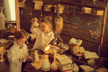 Fototapeta na wymiar preschooler scientists studying chemistry in the lab with owl sitting on the lamp