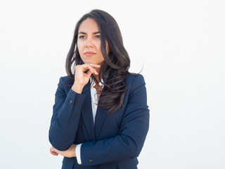 Serious pensive professional thinking over business strategy. Young Latin woman in office suit...