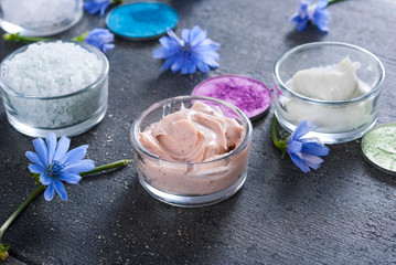 moisturizer, bath salt and face powder samples on dark wooden background
