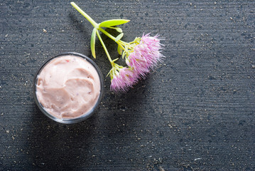 moisturizer with pink flowers on old black wood table