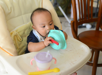 Asian baby boy 6 months old eating by himself with Baby Led Weaning (BLW) method, Self-Feeding