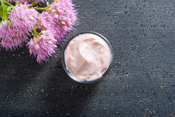 moisturizer with pink flowers on old black wood table