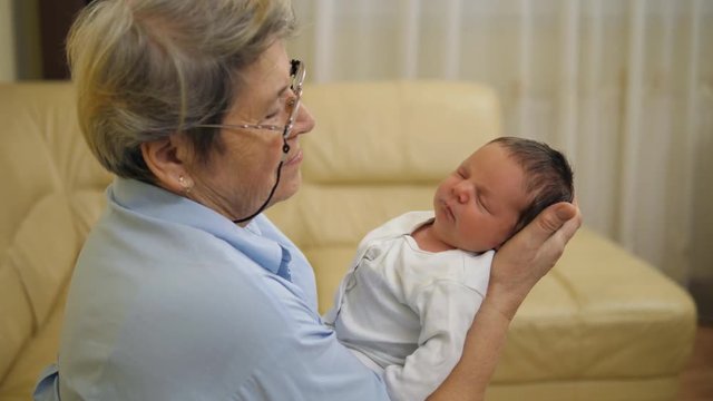 Old grandmother holding and looking at newborn baby, hopes and dreams for future