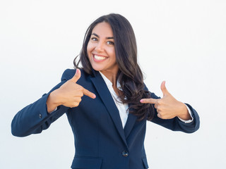 Happy joyful businesswoman pointing index fingers at herself. Cheerful delighted young Latin woman in formal suit proud of herself. Self pride concept
