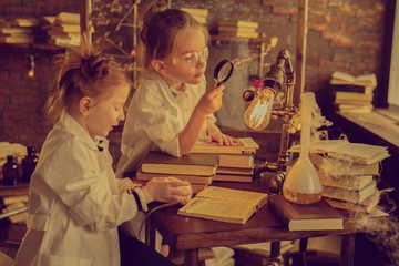 two girls using magnifying glass for chemical experiment in the laboratory