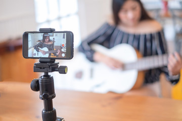 Happy girl blogger at cafe live guitar on broadcasts website for viewers to see through, blogger concept