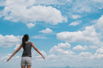 lifestyle concept - beautiful happy woman enjoying summer outdoors over blue sky.
