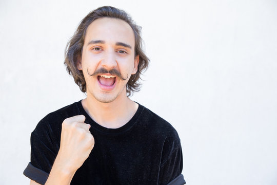 Successful Man With Handlebar Mustache Looking At Camera. Smiling Young Man With Raised Fist. Concept Of Success