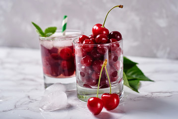 Fresh ripe cherries in sparkling glass on gray table background, copy space