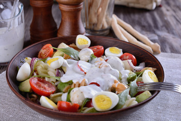 Homemade salad of cherry tomatoes, arugula, mozzarella, quail eggs and pasta dressed with white sauce in a ceramic plate