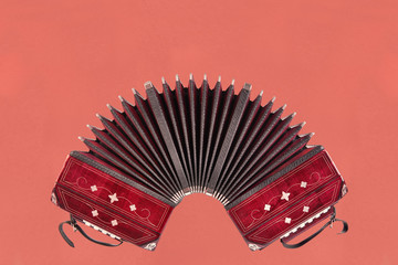 Bandoneon, tango instrument, front view oin pink paper background