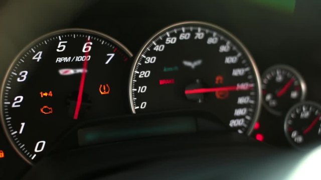 Dashboard speedometer and tachometer of a sports car. Includes ignition and dashboard lights, close-up.