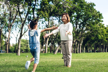 Fototapeta premium Portrait of happy grandmother and little cute girl enjoy relax together in summer park,little girl run to grandmother and hug.Family and togetherness