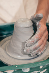 Creating a jar or vase of brown clay close-up. Master crock. Man hands making clay jug macro. The sculptor in the workshop makes a jug out of earthenware closeup. Twisted potter's wheel.