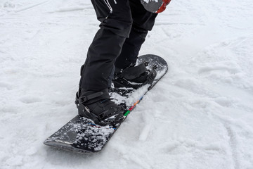 Detail of legs of young snowboarder in boots close-up. Winter sport, snowboard, leisure outdoor lifestyle