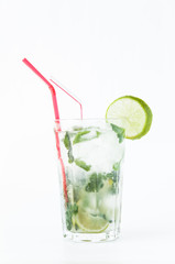 Mojito cocktail in a transparent glass with ice. Recipe for exotic drinks with mint, lime and white rum. Glass with a cocktail on a white background in the rays of the sun.