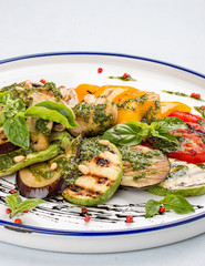 Grilled vegetables - tomatoes, zucchini, eggplant, sweet pepper, mushrooms. In a white plate
