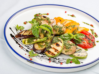 Grilled vegetables - tomatoes, zucchini, eggplant, sweet pepper, mushrooms. In a white plate