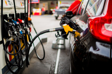 Refilling the car with fuel at the gas  station and blurry staff background, black car in gas station, refilling the car with fuel at the refuel station, the concept of fuel energy, Blurry image for