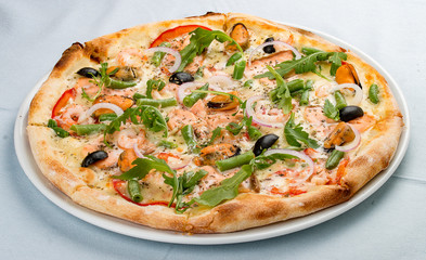 Delicious hot pizza with salmon, mussels, olives, tomatoes and various spices. On white background