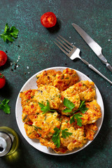 Chicken cutlets made from minced meat, with paprika, tomatoes and greens in a bowl on a dark stone table. Top view flat lay.