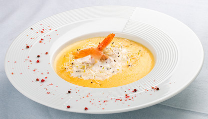 Cheese cream soup with parmesan and shrimp on a white plate