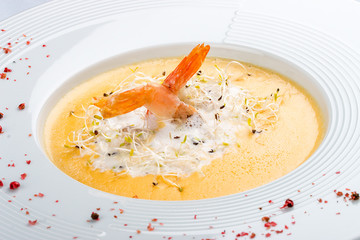 Cheese cream soup with parmesan and shrimp on a white plate