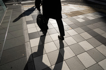 Silhouette of businessman, office guy holding bag walking to work in the morning in Tokyo, Japan