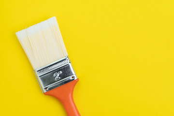 Orange painting brush on solid yellow background with copy space using as art, color palette or design concept
