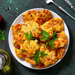 Chicken cutlets made from minced meat, with paprika, tomatoes and greens in a bowl on a dark stone table. Top view flat lay.