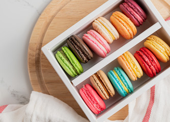 Colourful macaroons in white box top view background