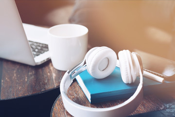 It's time to work. Headphones, cup of coffee, notebook and laptop on the table against defocused background. Copy space in upper left part