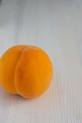 Top view of peach in foreground on white wooden background in vertical with copy space