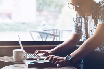 Multitasking. Handsome male freelancer in glasses working remotely indoors. Copy space on the left side