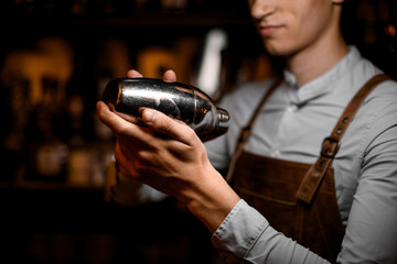 Male bartender holding in hands a steel shaker