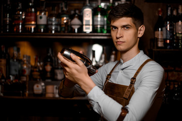 Attractive bartender holding in hands a steel shaker
